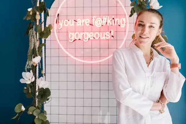 a woman standing beside a pink neon sign for nail salon sign ideas